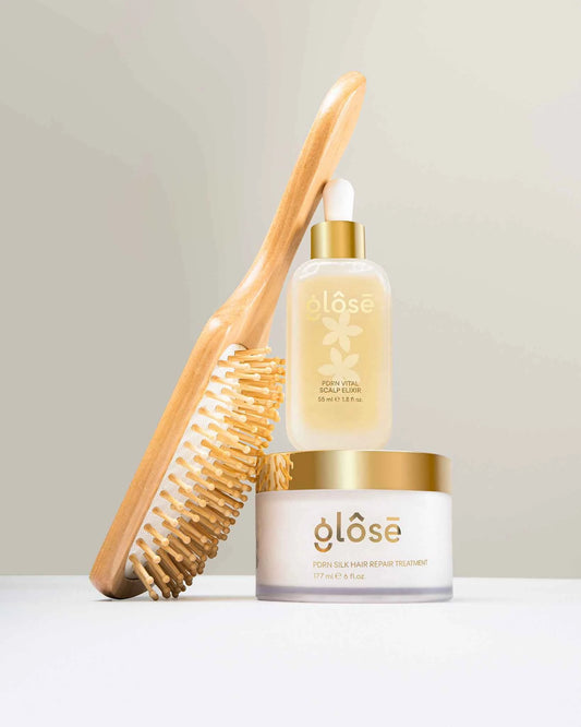 The Glôsē Method hair care ritual set displayed with a wooden paddle brush